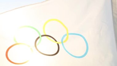 Olimpiyat bayrağı rüzgarda dalgalanıyor gökyüzünün arka planına ve yakın planda güneşe karşı. Olimpik Spor Oyunları 'nın sembolü, hayranlar. Kaluga, Rusya, 20 Mayıs 2021