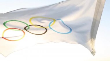 Olimpiyat bayrağı rüzgarda dalgalanıyor gökyüzünün arka planına ve yakın planda güneşe karşı. Olimpik Spor Oyunları 'nın sembolü, hayranlar. Kaluga, Rusya, 20 Mayıs 2021