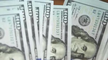 Elleri faturaları sayar, dolarları tahtadan bir masaya yatırır, banknotları çevirirler. Yüz dolar. Yakın plan 100 dolarlık banknotlar. Finans, ekonomi, mali planlama, ekonomi, tasarruflar.