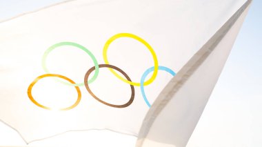 Olimpiyat bayrağı rüzgarda dalgalanıyor gökyüzünün arka planına ve yakın planda güneşe karşı. Olimpiyat Spor Oyunları 'nın sembolü, müsabakaların taraftarı. Kaluga, Rusya, 20 Mayıs 2021 