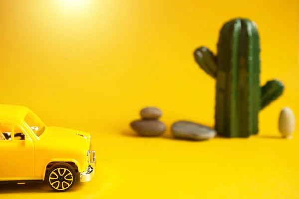 Summer trip by car-a yellow car on a background with a cactus-a tour to the desert, to the sea. Independent travel, domestic tourism. Taxi for a sightseeing tour. Copy space