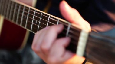 Adam gitar çalıyor ve gün batımında açık havada şarkı söylüyor. Elini bir gitarın fretboard 'una koyup parmaklarını tellerden geçirir ve akorları kıskaçlar. Enstrümantal müzik, notalar üzerine gitar dersi