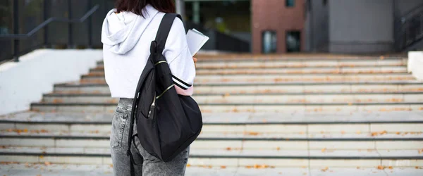黒いバックパックとノートを手にした女子学生が大学の前の階段に立っている 高等教育 学校の年の初め 学校に戻る コピースペース — ストック写真