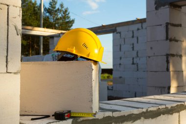 Gözenekli beton bloklardan yapılmış inşaat halindeki bir evin penceresinde inşaat başlığı ve mezura ölçüsü. Çalışma akışı, mimarlık ve mühendislik, bina. İş güvenliği ve araçlar. 