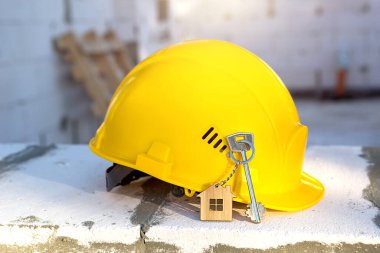 Gözenekli beton bloklardan yapılmış konutların penceresinde sarı baret ve anahtar var. Anahtar inşaatı, müstakbel ev, mühendislik, bina. İş güvenliği. Boşluğu kopyala