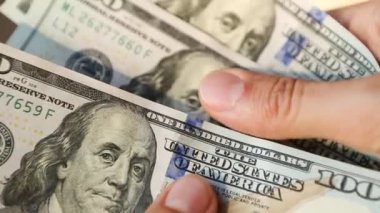 El, 100 dolarlık banknotu yığının içine koyar ve bir banknot alır. Nakit para, 100 dolarlık banknotlar. Finans, ekonomi, mali planlama, ekonomi, tasarruflar.