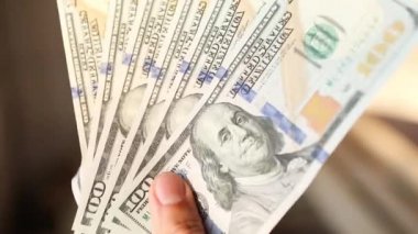 El, 100 dolarlık banknotu yığının içine koyar ve bir banknot alır. Nakit para, 100 dolarlık banknotlar. Finans, ekonomi, mali planlama, ekonomi, tasarruflar.