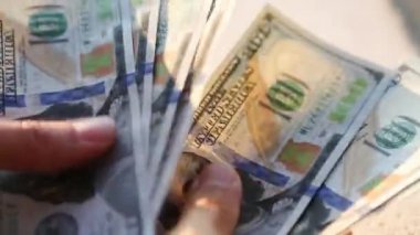 El, 100 dolarlık banknotu yığının içine koyar ve bir banknot alır. Nakit para, 100 dolarlık banknotlar. Finans, ekonomi, mali planlama, ekonomi, tasarruflar.