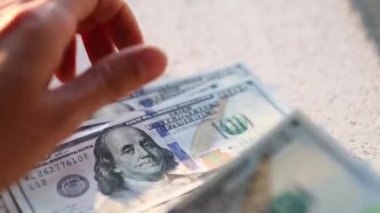 El, 100 dolarlık banknotu yığının içine koyar ve bir banknot alır. Nakit para, 100 dolarlık banknotlar. Finans, ekonomi, mali planlama, ekonomi, tasarruflar.