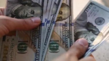 El, 100 dolarlık banknotu yığının içine koyar ve bir banknot alır. Nakit para, 100 dolarlık banknotlar. Finans, ekonomi, mali planlama, ekonomi, tasarruflar.