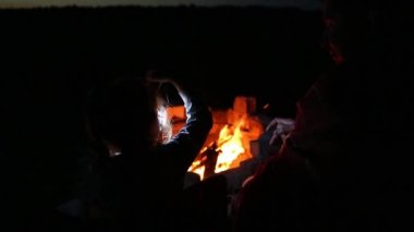 Baba ve kızı, yazın açık havada, ateşin yanında otururlar. Aile kamp gezisi, kamp ateşi etrafında buluşmalar. Babalar Günü, barbekü. Kamp feneri ve çadır.