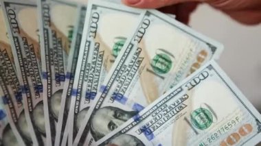 Eller paraları sayar, dolar kaydırır, yelpaze gibi yayılır, banknotları çevirir. Yüz dolar. Yakından 100 dolarlık banknot yığını. Finans, ekonomi, mali planlama, ekonomi, tasarruflar.