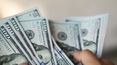 Eller paraları sayar, dolar kaydırır, yelpaze gibi yayılır, banknotları çevirir. Yüz dolar. Yakından 100 dolarlık banknot yığını. Finans, ekonomi, mali planlama, ekonomi, tasarruflar.