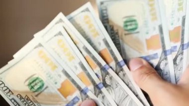Eller paraları sayar, dolar kaydırır, yelpaze gibi yayılır, banknotları çevirir. Yüz dolar. Yakından 100 dolarlık banknot yığını. Finans, ekonomi, mali planlama, ekonomi, tasarruflar.