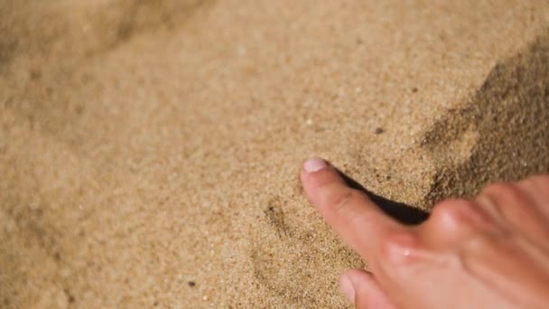 用你的手指在沙滩上画一个心是一个爱海滩度假的迹象 海滩上的热黄色易碎沙子 度假胜地 — 图库视频影像