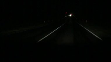 Geceleri otoban, sınırlı görüş koşullarında araba kullanmak. Farlar asfalttaki noktalı yol işaretlerini aydınlatıyor, yaklaşan trafik ışıldıyor. Güvenlik, gece gezintisi, kamyoncu