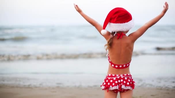 Річна Дівчинка Червоному Купальнику Санта Капелюсі Пляжі Піднімає Руки Легкого — стокове відео