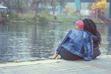 Eşcinsel çiftler arasında aşk. Lezbiyen gibi oturmak ve dışarıda kucaklaşmak. Arka plan