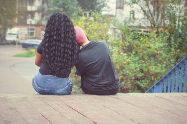 Eşcinsel çiftler arasında aşk. Lezbiyen gibi oturmak ve dışarıda kucaklaşmak. Arka plan