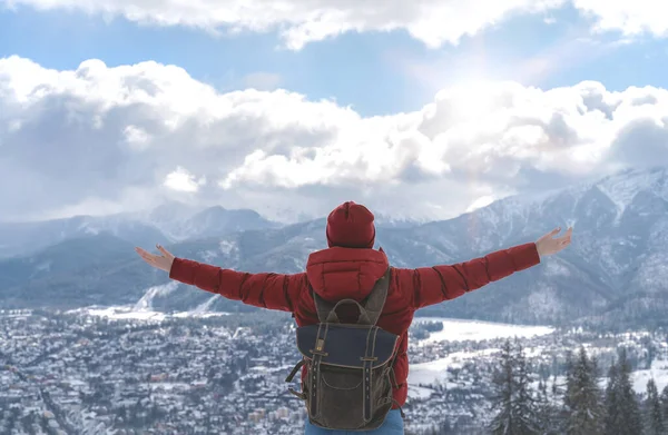 Happy person enjoy life with hands up on background of mountains and blue sky with clouds. Girl travels with backpack. Concept of freedom strength mind. Human and nature