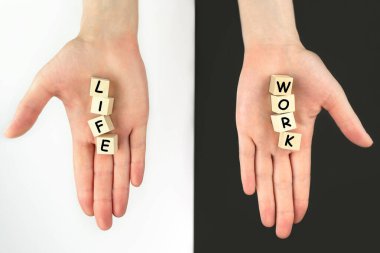 Work and life. Wooden cubes on a black white background in hands. The concept of balance, harmony, no stress. Planning and selection