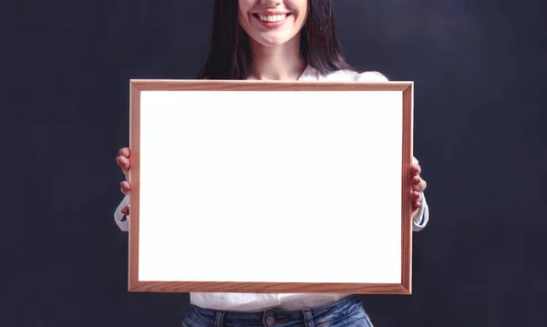 Elinde reklam panosu olan gülümseyen bir kadın. Poster çerçeveli beyaz gömlekli kız.