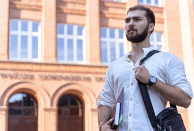 Enstitü yakınlarında bir iş adamı. Beyaz tişörtlü, sakallı, kendine güvenen yakışıklı, ciddi bir adam.