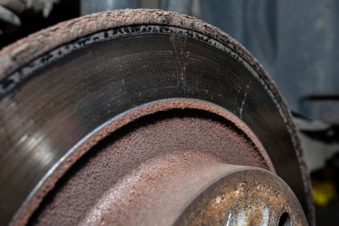 Eski ve hasarlı arka fren diskleri, kalibreli ve fren pedleri arabada, bir atölyede araba kaldırmada..