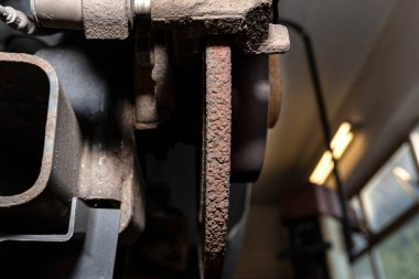 Eski ve hasarlı arka fren diskleri, kalibreli ve fren pedleri arabada, bir atölyede araba kaldırmada..