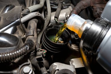 Araba tamircisi, bir araba atölyesindeki plastik tanktan motora yeni araba yağı döktü..