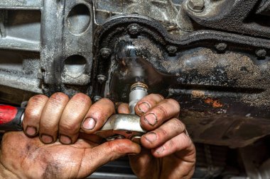 Tamirci, bakır bir vidayla yeni bir vidayı mazot motoruyla yağ torbasına vidalıyor..