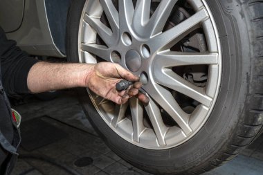 Araba tamircisi civataları alüminyum kenarları merkeze vidalamak için yerleştirir..