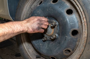 Araba tamircisi vidaları takar. Çelik halkaları merkeze takar..