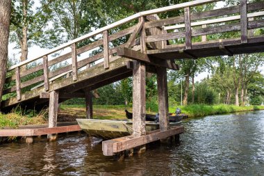 Hollanda 'da bitki ve binaların arka planındaki bir kanalın üzerindeki tahta süslemeli köprü..