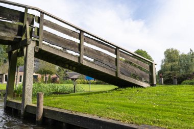 Hollanda 'da bitki ve binaların arka planındaki bir kanalın üzerindeki tahta süslemeli köprü..
