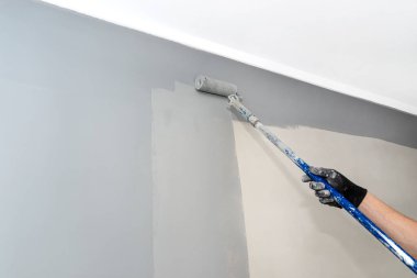 Ressam evi boyayarak boyayı uzatılmış bir sopayla griye boyuyor..