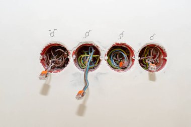 Odanın duvarına yerleştirilmiş turuncu bir kutudan çıkan elektrik kabloları, elektrik bağlantısına bağlı kablolar..