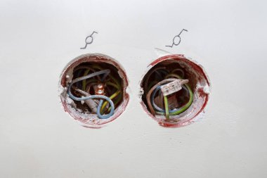 Odanın duvarına yerleştirilmiş turuncu bir kutudan çıkan elektrik kabloları, elektrik bağlantısına bağlı kablolar..