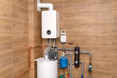 Doğal gaz için modern bir gaz kazanı, seramik fayanslarla kaplı bir kazan dairesine yerleştirilmiş..