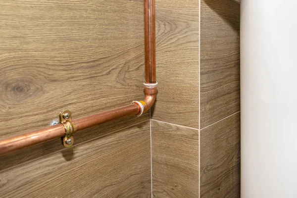 Doğal gaz tesisatı için bakır borular, seramik fayanslarla kaplı bir kazan dairesinin duvarına bağlı..