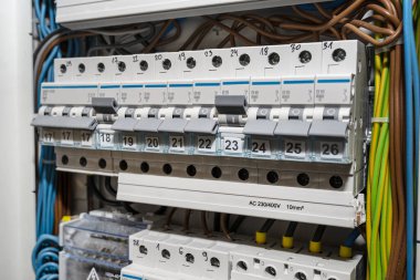 Kapalı ve ON pozisyonunda tek fazlı fitiller ve kapalı konumda üç fazlı fitiller, ev sigorta kutusuna yerleştirilmiş, görünür elektrik kabloları.