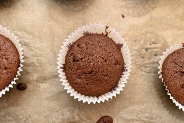 Fırında pişmiş beyaz kağıda sarılı kahverengi çikolatalı kekler, fırın kağıdının üzerinde yatıyorlar..