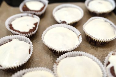 Beyaz kağıda sarılı çikolatalı kek ve beyaz kremayla kaplı, fırında pişmiş, fırın kağıdının üzerine uzanmış..