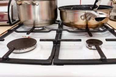 Mutfaktaki kapalı bir gaz sobasının üzerinde paslanmaz çelik bir tencere ve kızartma tavası..