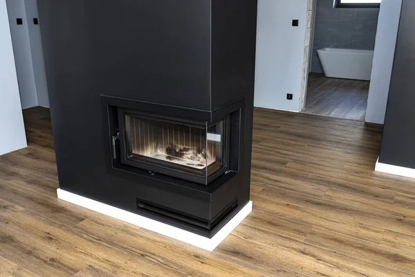 Modern bir şömine, oturma odasında yanma odası kapalı, siyaha boyanmış, köşesi yıkanmış..