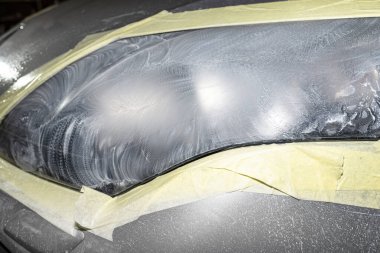 Farlar aşındırıcı macunla kaplıdır ve cilalanmaya hazır koruyucu bir bantla sabitlenir..