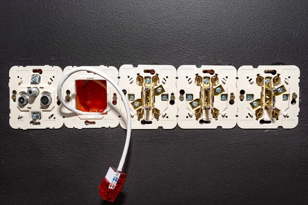 Odadaki bilgisayar prizine hazır RJ45 modülü ile duvardan çıkan bir ağ kablosu, görünür elektrik ve televizyon prizleri.