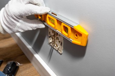 Bir elektrikçi odanın duvarındaki elektrik kutusuna çift topraklı bir elektrik prizi yerleştirir ve prizi ruh seviyesini kullanarak yerleştirir..