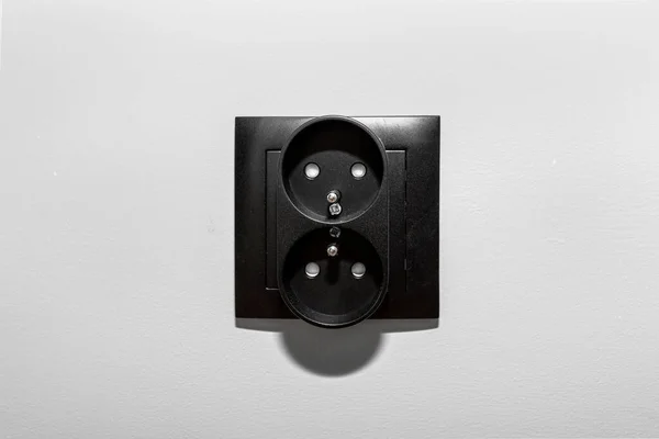 双电源插座的黑色框架 其接地在房间灰墙上 — 图库照片