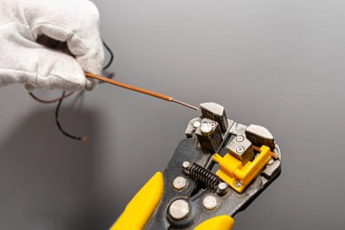 Bir elektrikçi faz kablosunu montaj için otomatik yalıtım striptizcisi kullanır..